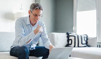 Man sitting on couch looking at laptop. 