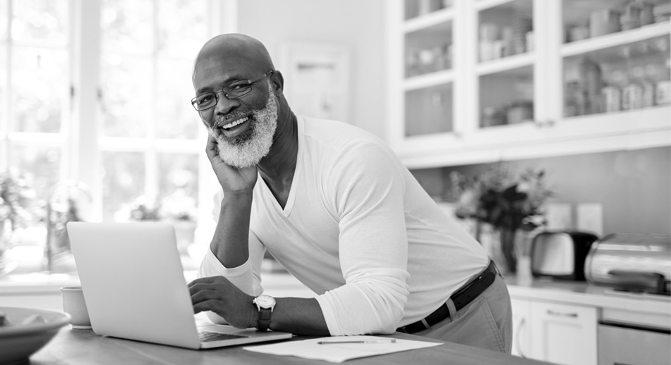 A senior man takes a break from looking at his laptop computer.