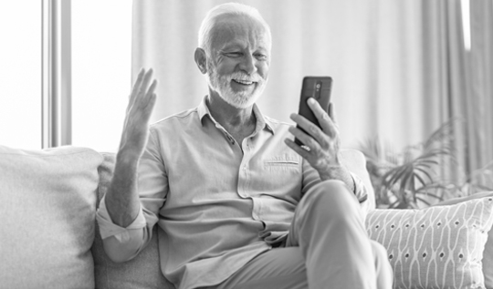 A senior man exclaims excitement over Blue Cross Medicare Advantage plans displayed on his phone.