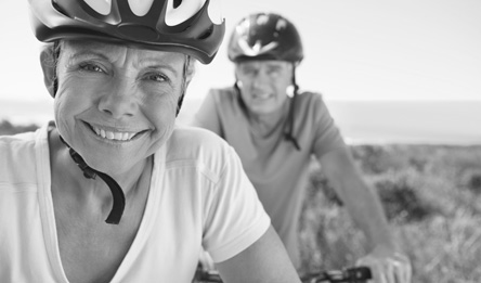 A man and woman smile while riding bikes.