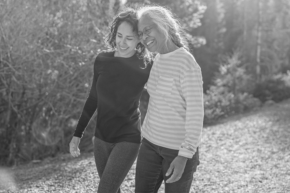 Two women smile as they walk arm in arm.