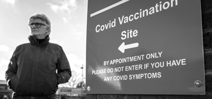 Person standing next to a COVID vaccination site sign