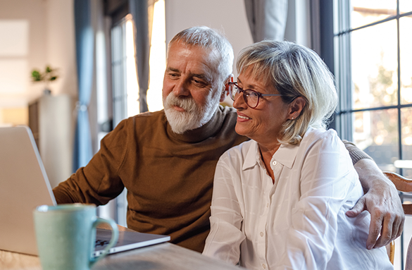 Man and woman smiling in front of a laptop computer