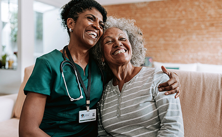 A doctor and a woman smile and hug each other.
