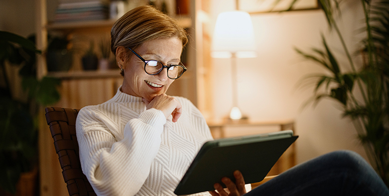 An older woman reads the Best of Health newsletter on her tablet in the comfort of her home.