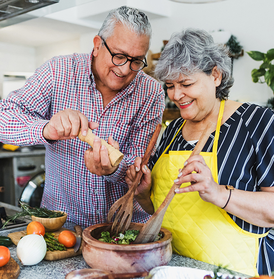 An older couple enjoy making a meal together.