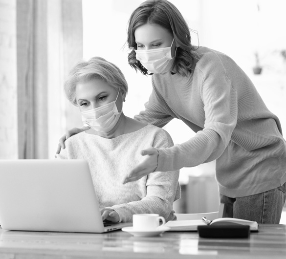 Two masked women in front of a laptop