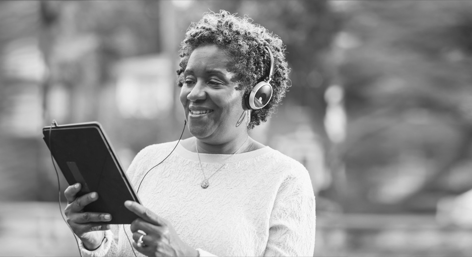 Woman looking at a tablet wearing headphones