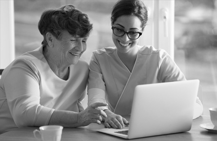Two smiling women looking at a laptop