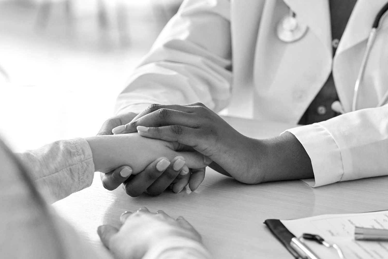 A doctor places their hands on another person's hand.