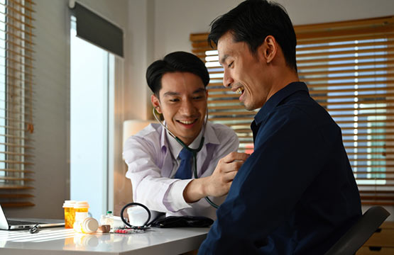 A man checks another man's heart rate with a stethoscope.
