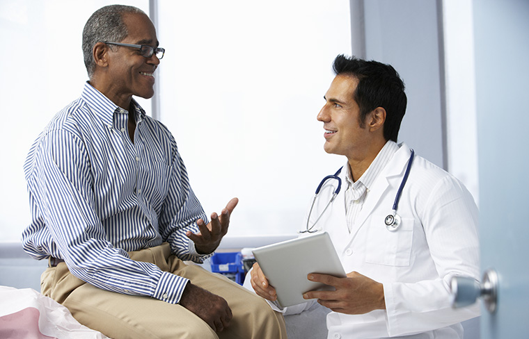 A male doctor discusses care with an older male patient.