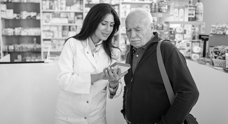 A pharmacist helps a man with his prescription.