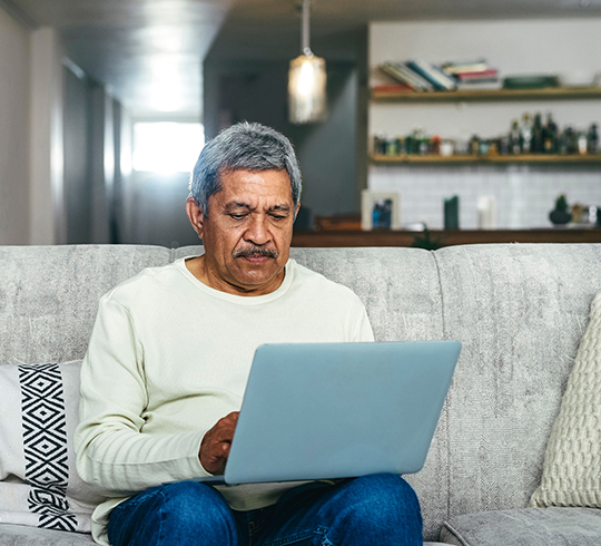 A person sits on a couch looking at a laptop