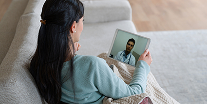 A woman smiling while on a virtual appointment with her doctor on a laptop screen