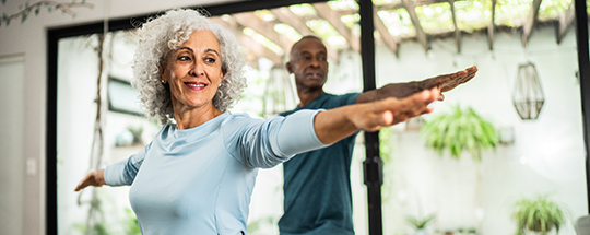 Two people smile as they do stretching exercises