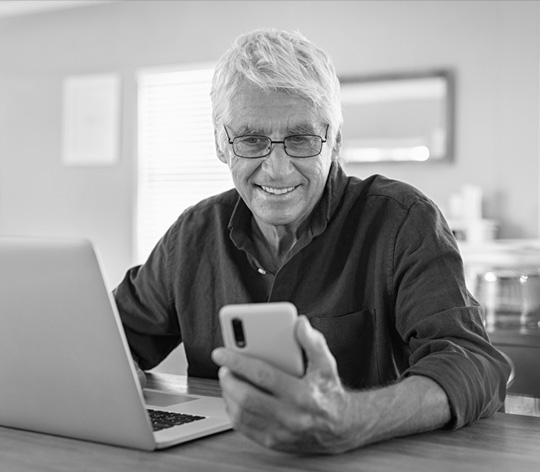 Man with a phone and a laptop