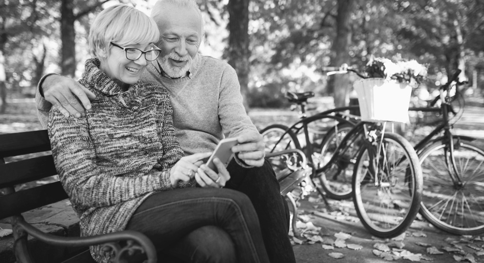 Couple sitting on a bench looking at a phone