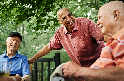 Three smiling older men talking while sitting outside