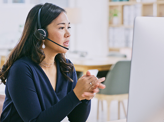 A woman who's a customer service representative wears a headset while talking to a member.