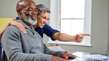 Woman points at computer over man's shoulder