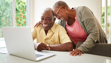 Husband and wife laugh as they look at a computer