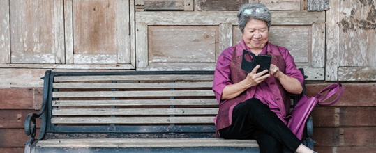 A woman sits on a bench and looks at her phone.