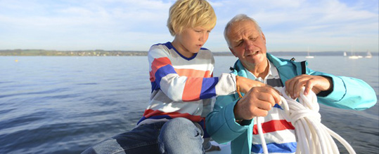 An older man and a little boy go sailing together.