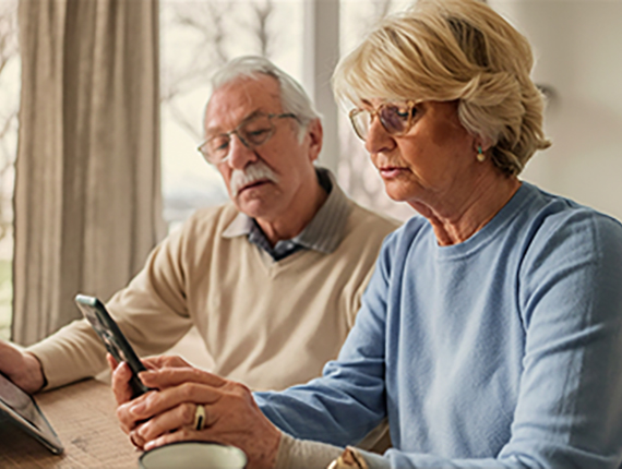 An senior couple look at a mobile device together