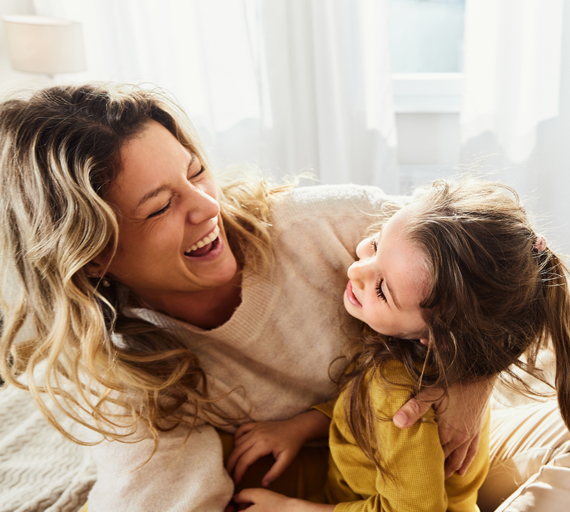 A smiling woman and young child play together.