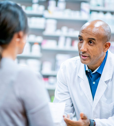 A healthcare provider speaking with a patient in a pharmacy or clinic setting.