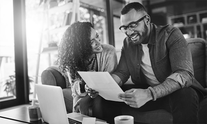 Two people sitting at home looking at paperwork together.