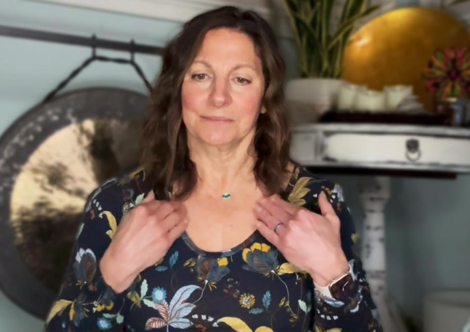 A woman touches points on her shoulders.