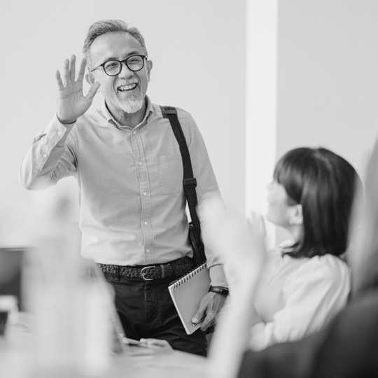 A health insurance agent stands and waves at a meeting