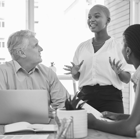 People in a meeting listen to a woman standing speaking