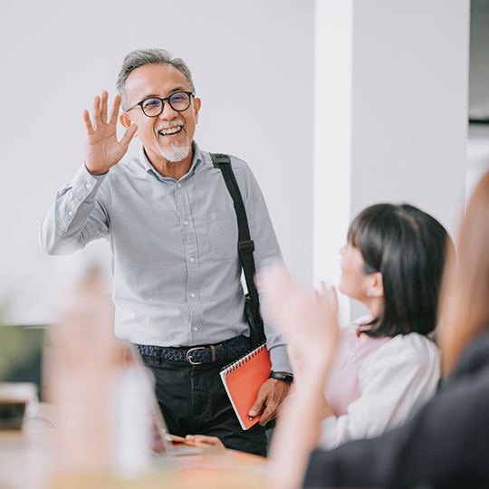 A health insurance agent stands and waves at a meeting