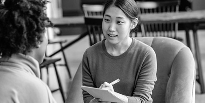 A woman takes notes as she talks to another person