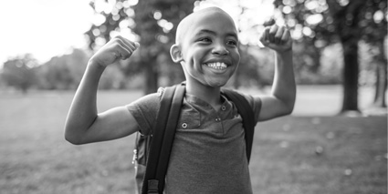 A boy wearing a backpack raises his hands in the air