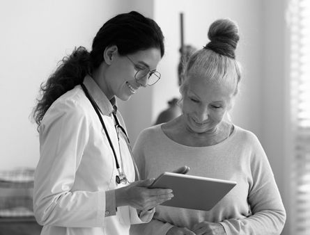 A smiling doctor and patient look at a tablet 
