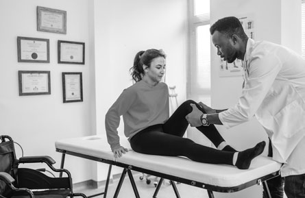 A woman has her leg examined by a health care provider