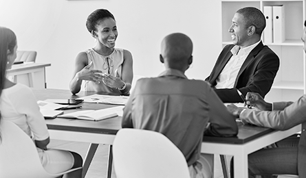 Five people sitting at a table in a meeting