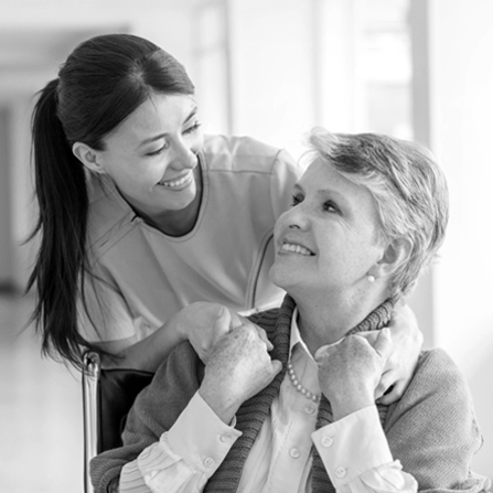 A nurse and patient smiling at each other and holding hands