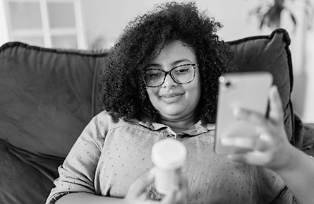 A woman looks at her prescription and her mobile phone