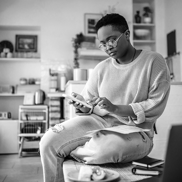 A woman sits in her kitchen using her mobile device