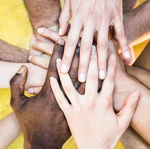 A diverse group of people place their hands on top of each other.