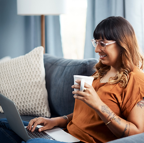 A woman sitting on a couch with her laptop and coffee