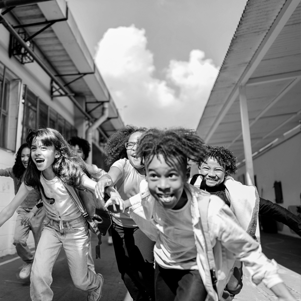 A group of children run and laugh during school recess.