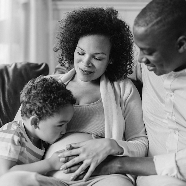A little boy kisses his mother's pregnant belly. 