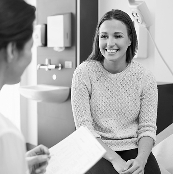 A woman smiles as a health care provider takes notes.