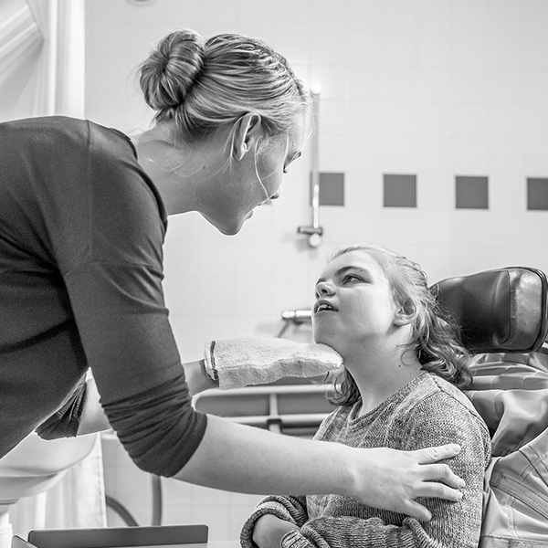 A woman helps a young girl in a wheelchair